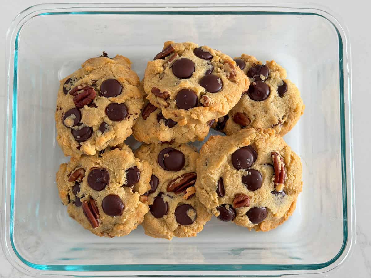 Almond flour chocolate chip cookies are stored in a glass container.
