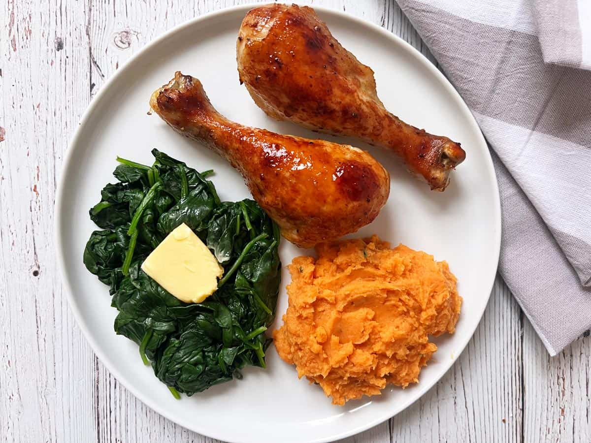 Honey garlic chicken is served with spinach and mashed sweet potatoes.