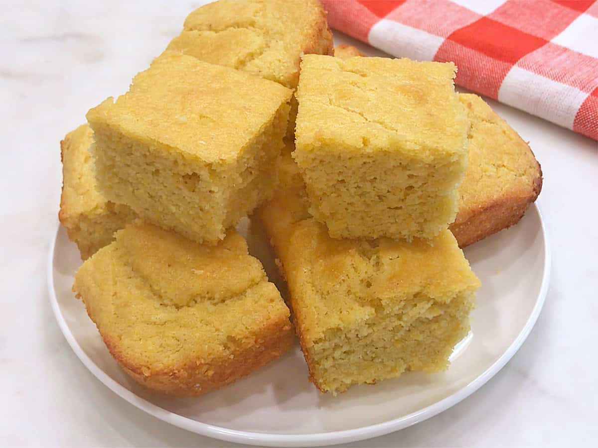 Keto cornbread squares are served on a white plate.