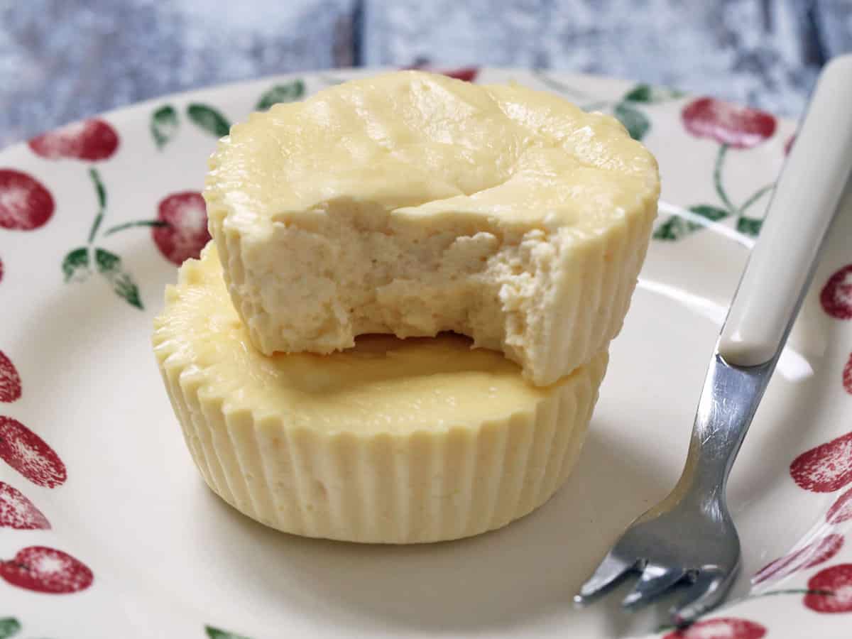 Two mini cheesecakes are served on a plate with a fork.