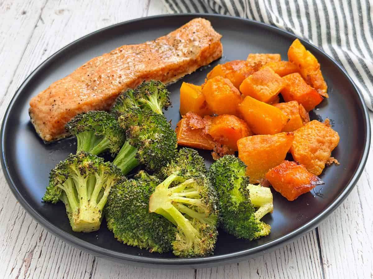 Baked salmon with heavy cream is served with broccoli and butternut squash.