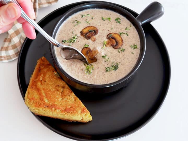 Using a spoon to taste the soup.