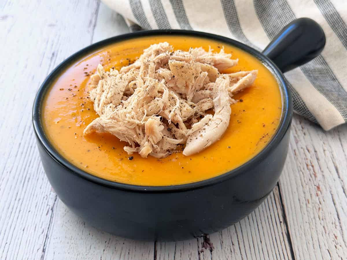 Butternut squash soup is topped with shredded chicken.