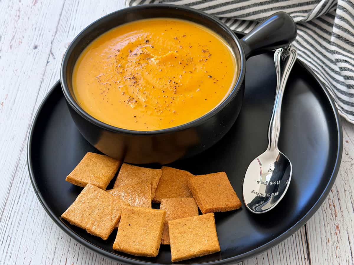 Butternut squash soup is served with crackers.