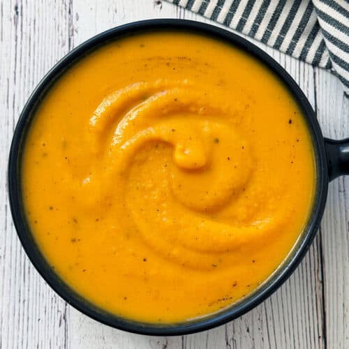 Butternut squash soup is served in a black bowl.