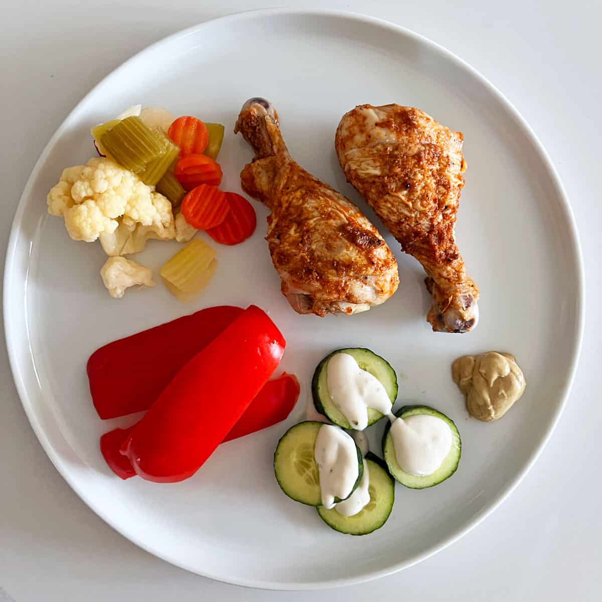 Cold drumsticks are served with veggies and pickles.