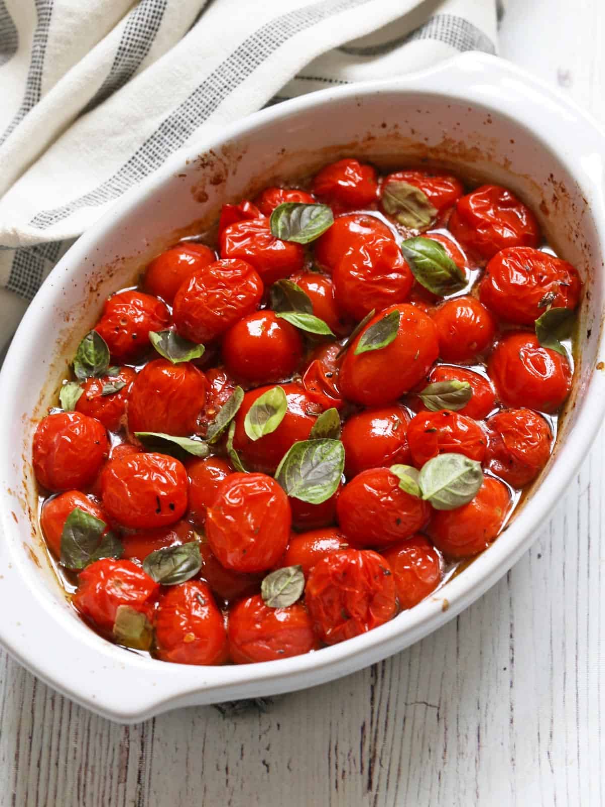 Roasted cherry tomatoes are served in a white baking dish.