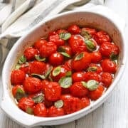 Roasted cherry tomatoes are served in a white baking dish.