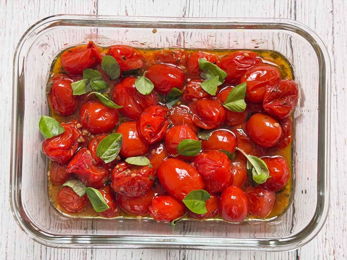 Roasted cherry tomatoes are stored in a glass container.