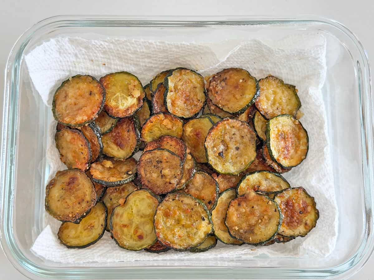 Zucchini chips are stored in a glass container.
