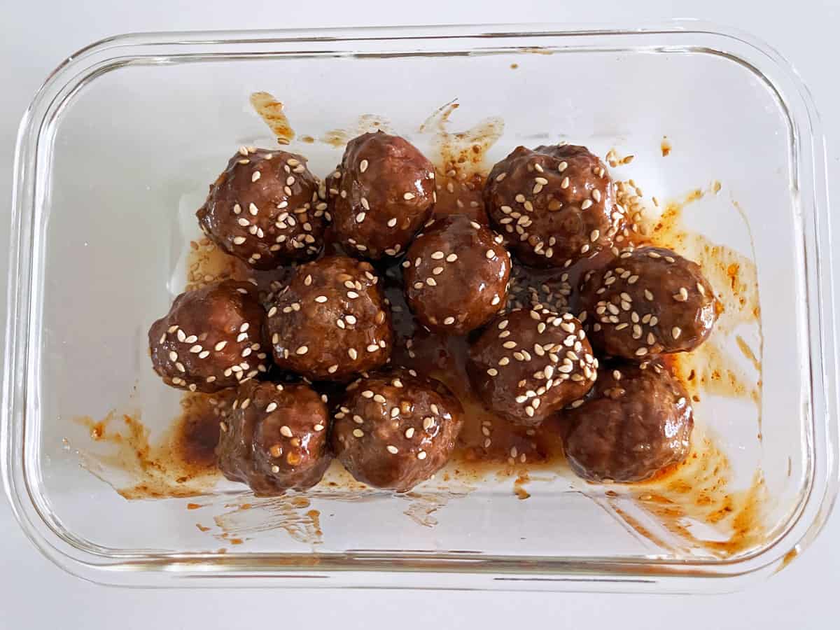 Asian meatballs leftovers are stored in a glass container.