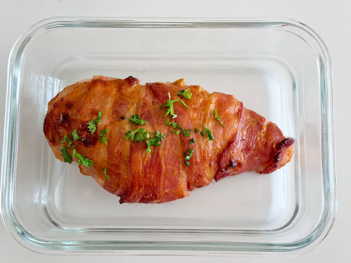 Bacon wrapped chicken leftovers are stored in a glass container.
