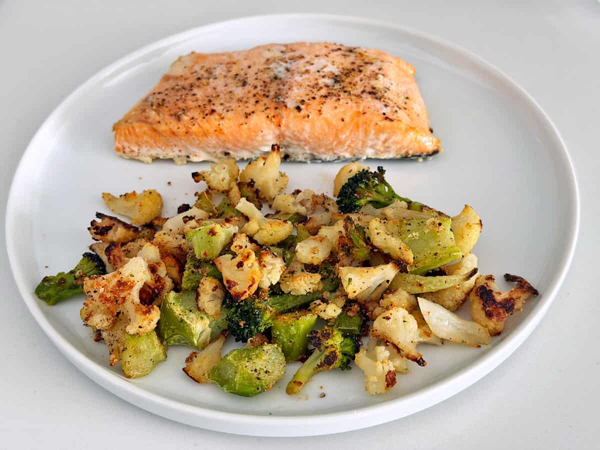 Roasted frozen broccoli and cauliflower are served with baked salmon.