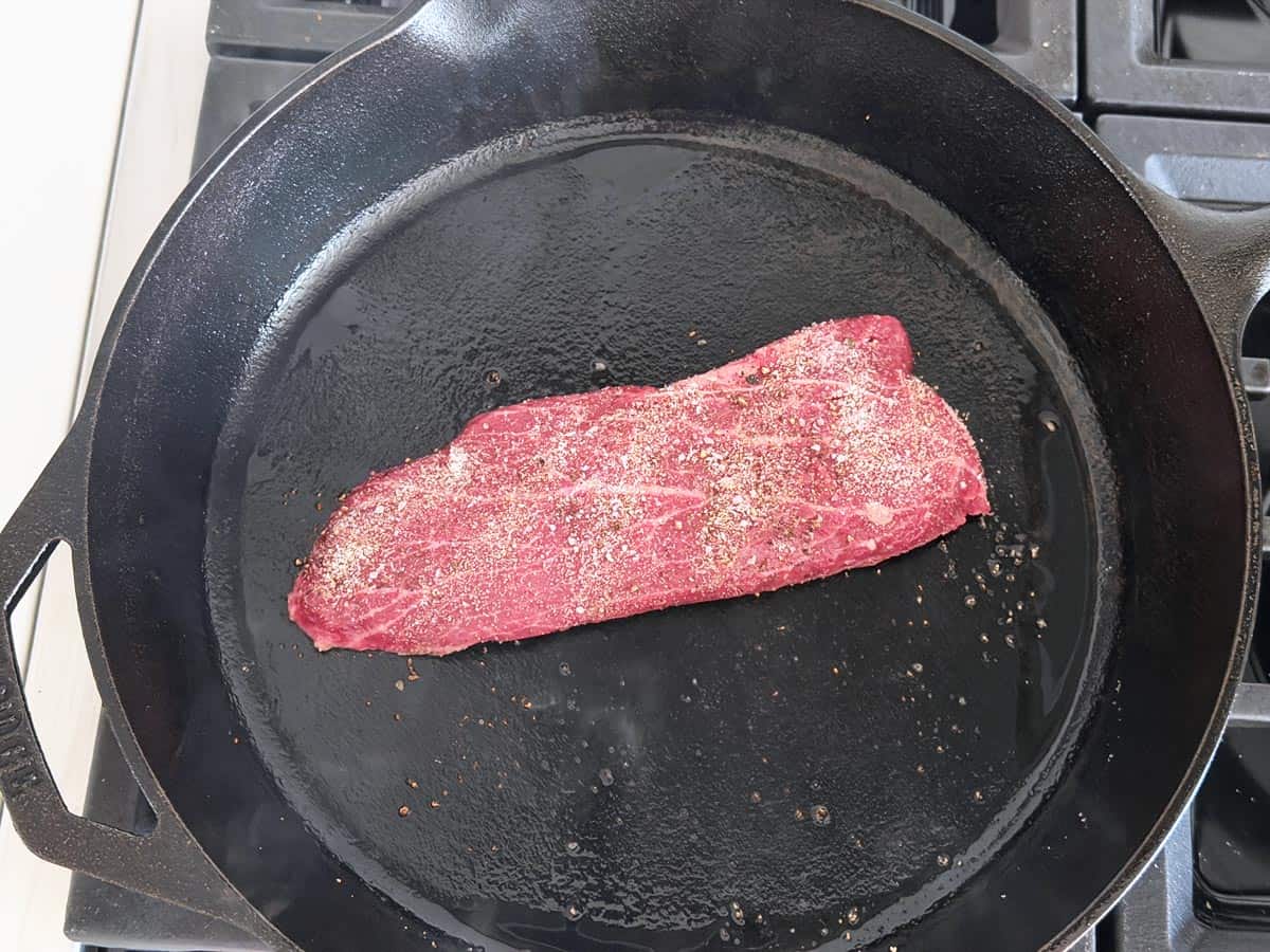 Flat iron steak in a cast-iron skillet.