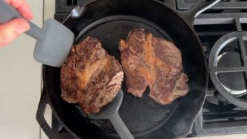 Flipping the steaks to finish cooking.