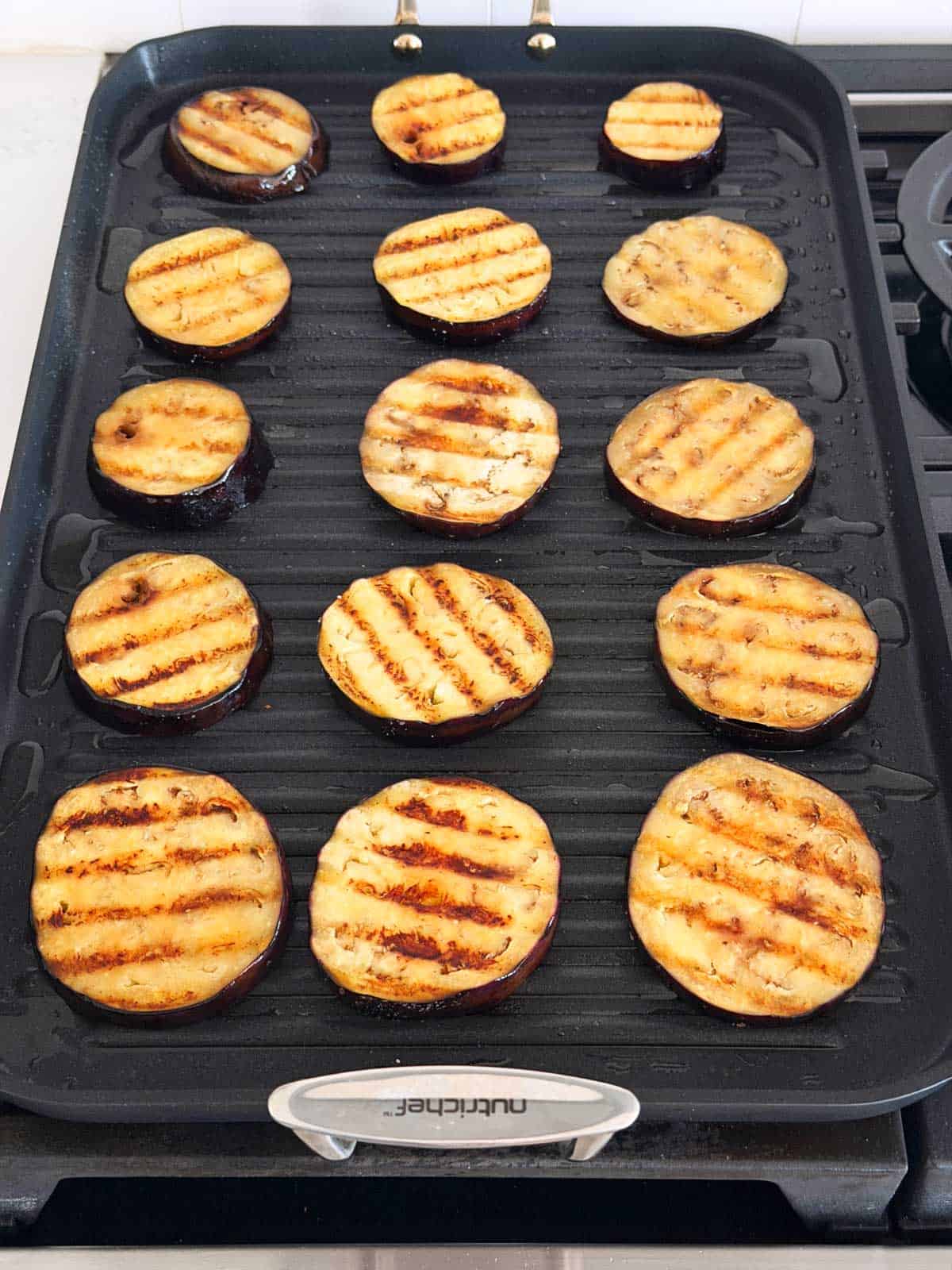 Grilling eggplant slices on a double burner grill pan.