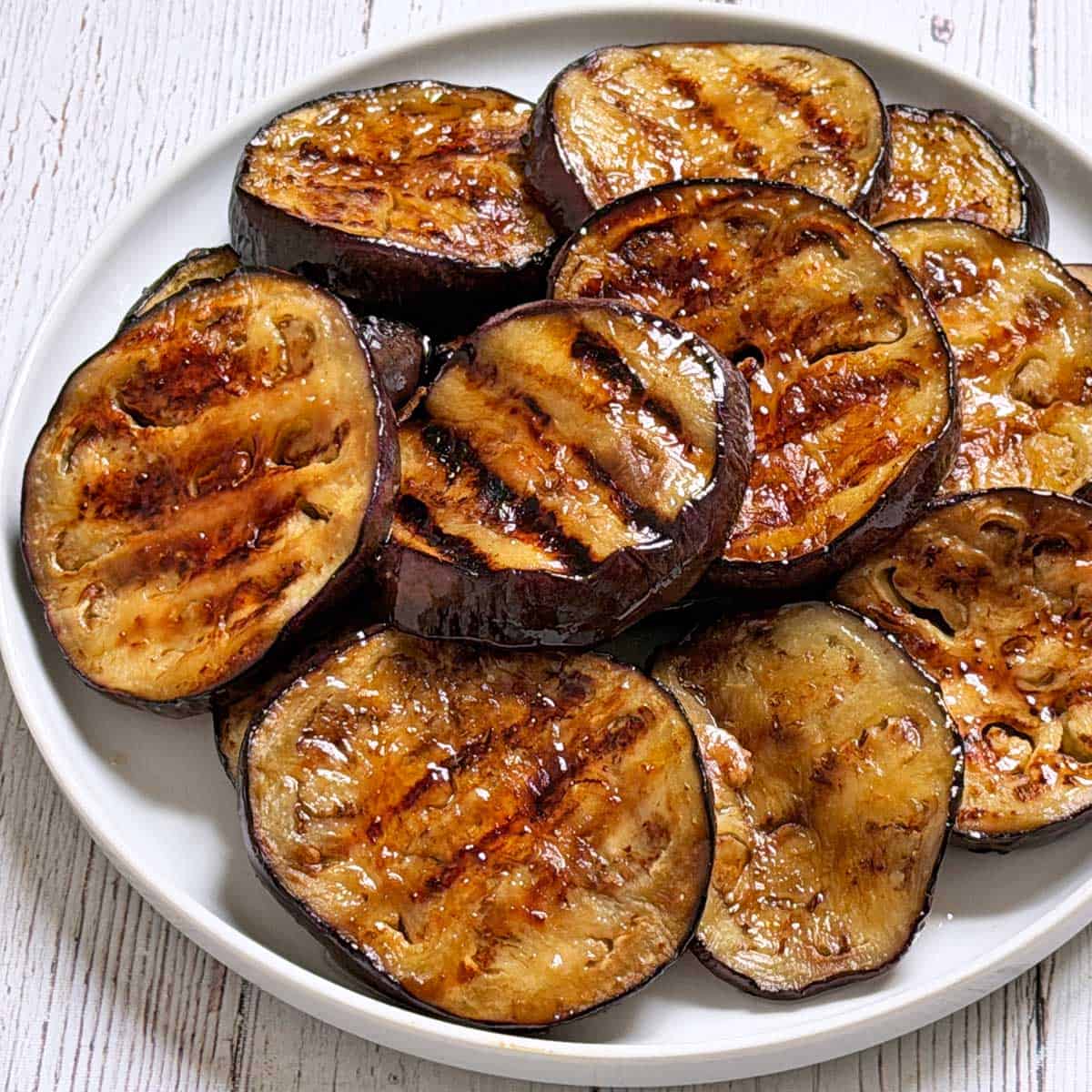 Grilled eggplant is served on a white plate.